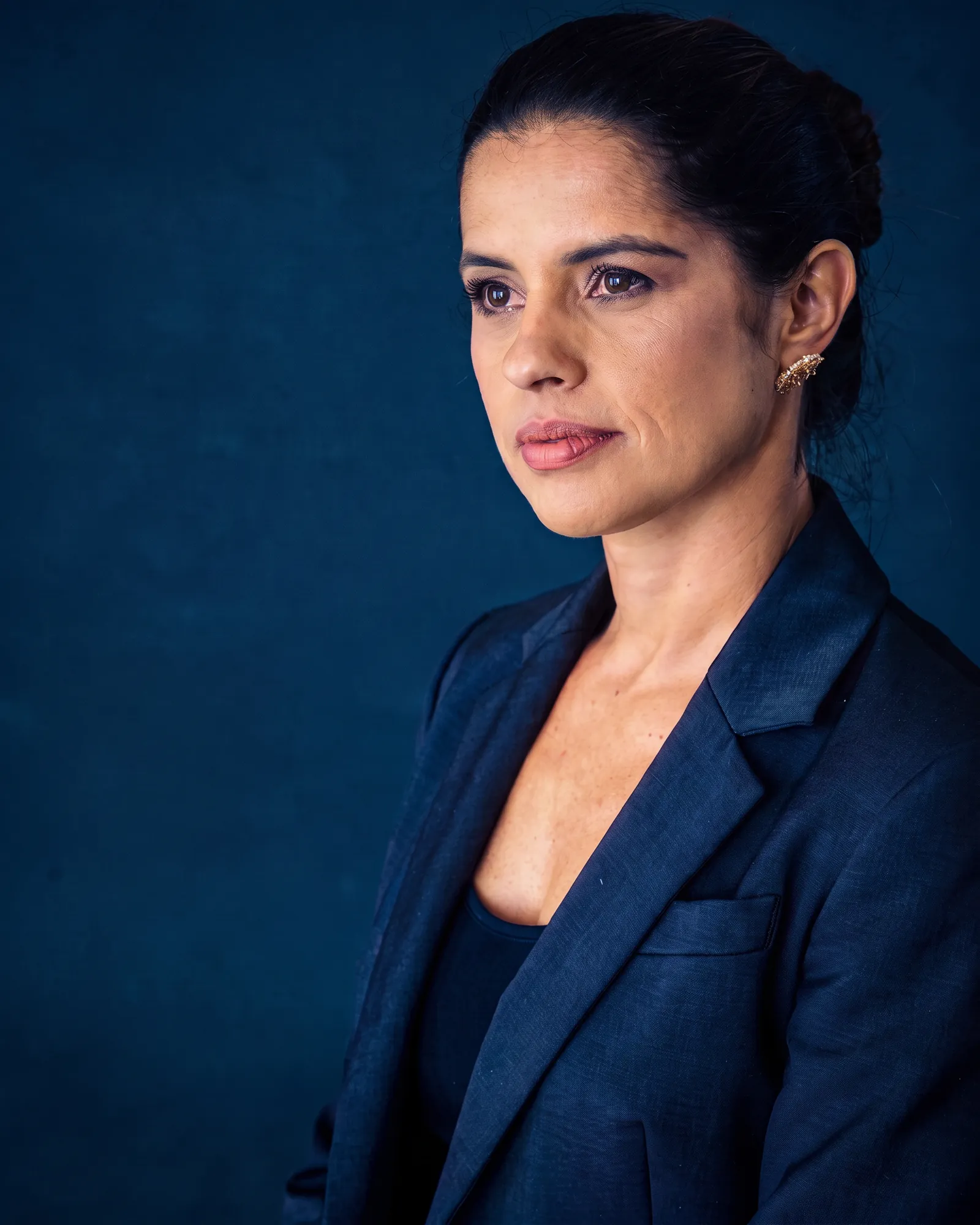Retrato editorial de uma consultora de blazer escuro, em perfil, com expressão serena e atenta